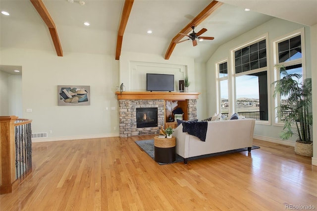 living room with visible vents, baseboards, lofted ceiling with beams, a stone fireplace, and light wood-style floors