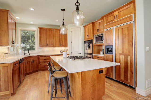 kitchen featuring a kitchen bar, light wood-type flooring, built in appliances, and a kitchen island