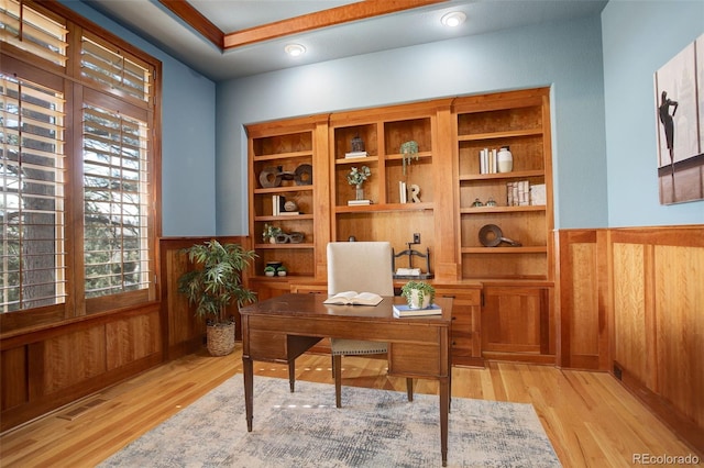 home office with a wainscoted wall, wood walls, light wood-type flooring, and visible vents