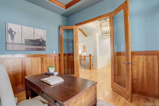 office with an inviting chandelier, wood finished floors, a wainscoted wall, and wood walls