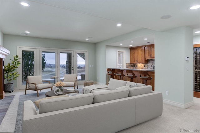 living area with visible vents, recessed lighting, baseboards, and light carpet