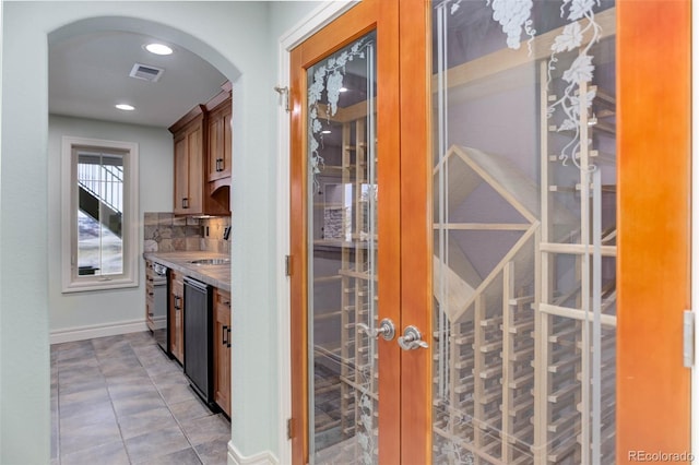 bar with dishwashing machine, light tile patterned floors, baseboards, recessed lighting, and arched walkways