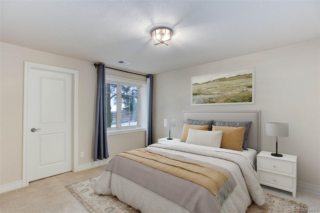 bedroom featuring visible vents, baseboards, light colored carpet, and a textured ceiling