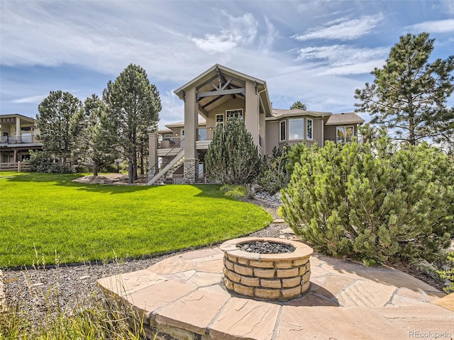 exterior space featuring stairway, an outdoor fire pit, stucco siding, a lawn, and a patio