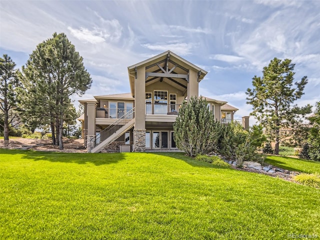 back of property with stairs, a deck, a lawn, and stucco siding