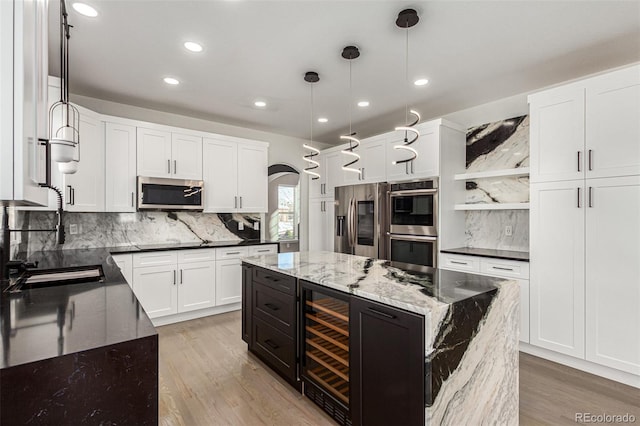 kitchen featuring pendant lighting, dark stone countertops, light wood-type flooring, appliances with stainless steel finishes, and a kitchen island