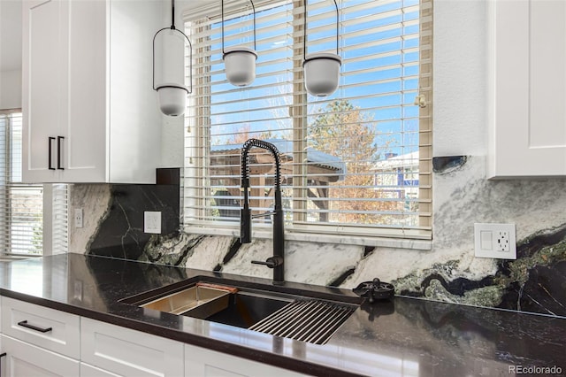 kitchen with decorative backsplash, white cabinetry, sink, and dark stone countertops