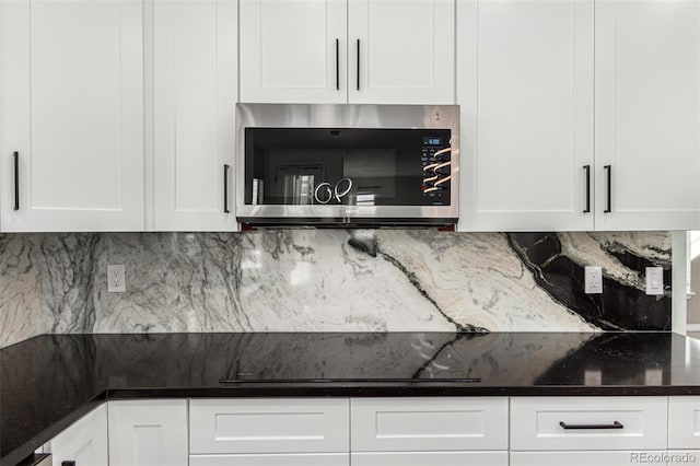 kitchen featuring decorative backsplash, white cabinetry, black electric stovetop, and dark stone counters