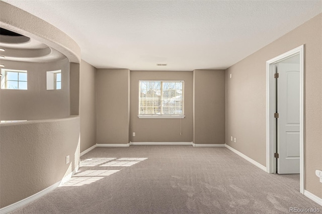 spare room with a textured ceiling and light carpet