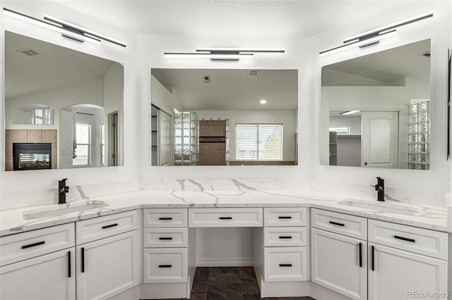 bathroom featuring a tiled fireplace, vanity, and a textured ceiling