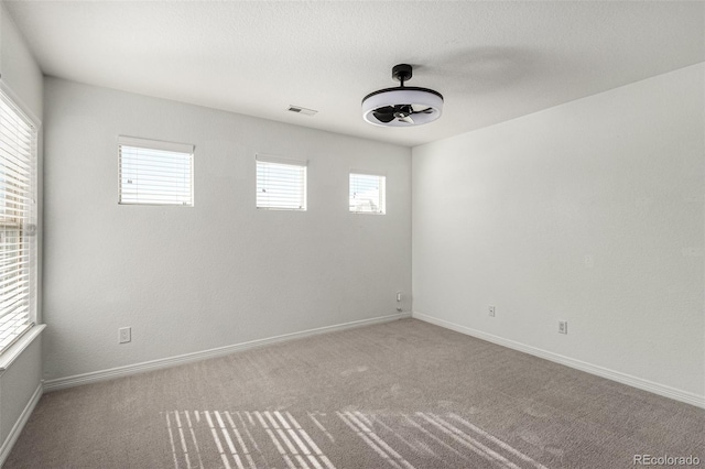 spare room with ceiling fan, carpet floors, and a wealth of natural light