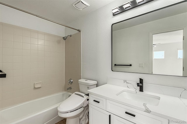 full bathroom featuring vanity, tiled shower / bath combo, and toilet