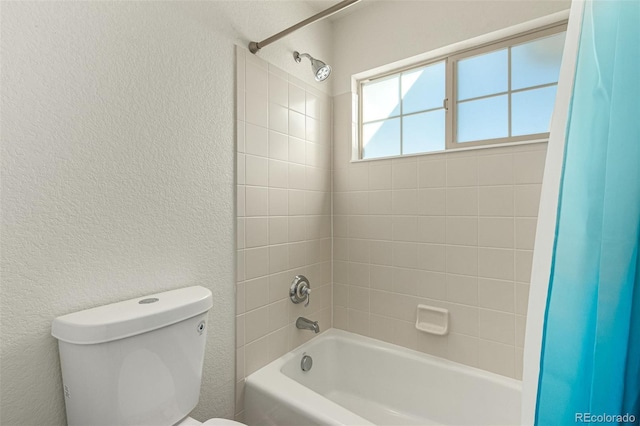 bathroom featuring toilet and tiled shower / bath