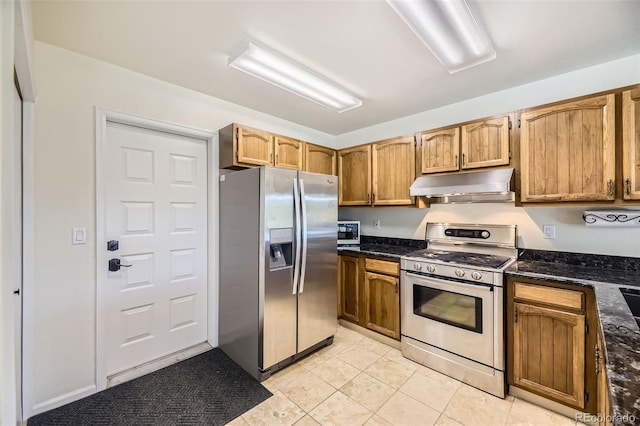 8414 S Otis St, Littleton, CO 80128 - kitchen with appliances with stainless steel finishes, under cabinet range hood, light tile patterned floors, dark stone counters, and brown cabinetry
