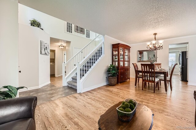5133 E Essex Ave, Castle Rock, CO 80104 - living room with a chandelier, a textured ceiling, stairs, light wood finished floors, and ornamental molding