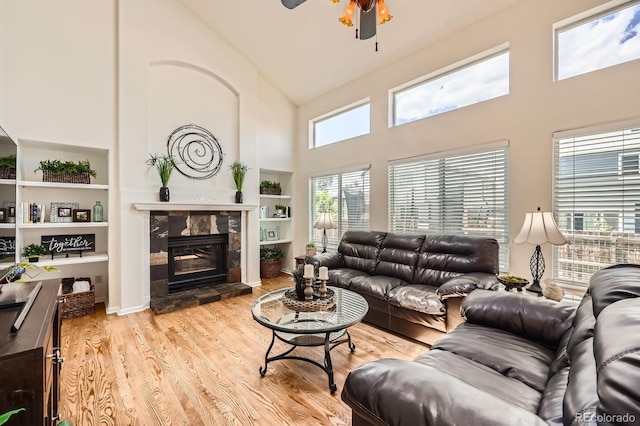 5133 E Essex Ave, Castle Rock, CO 80104 - living room featuring a high ceiling, ceiling fan, wood finished floors, a glass covered fireplace, and built in shelves