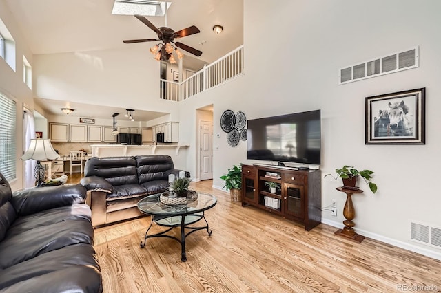 5133 E Essex Ave, Castle Rock, CO 80104 - living area featuring ceiling fan, a towering ceiling, light wood-style flooring, a skylight, and plenty of natural light