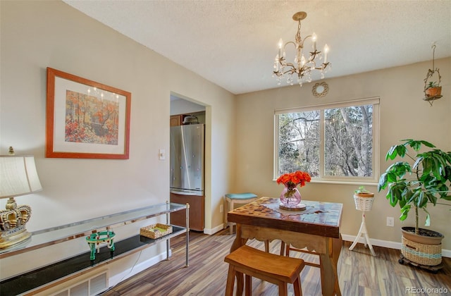 3006 Oro Blanco Dr, Colorado Springs, CO 80917 - dining space featuring baseboards, wood finished floors, a textured ceiling, and a chandelier