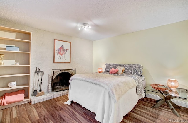 3006 Oro Blanco Dr, Colorado Springs, CO 80917 - bedroom with wood finished floors, a textured ceiling, and a fireplace