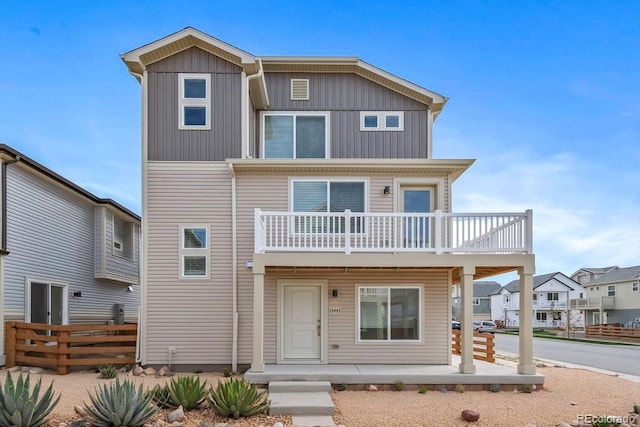 view of front facade featuring a balcony, fence, and board and batten siding