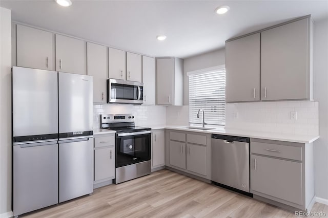 kitchen with stainless steel appliances, a sink, gray cabinetry, light countertops, and recessed lighting
