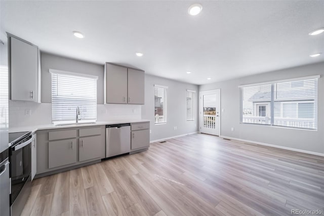 kitchen featuring gray cabinets, dishwasher, a sink, electric range oven, and light countertops
