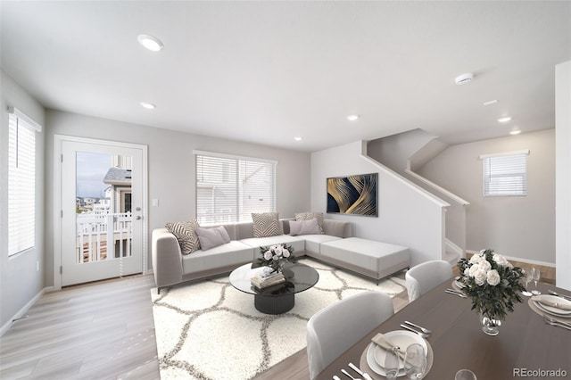 living area featuring plenty of natural light, light wood finished floors, recessed lighting, stairs, and baseboards