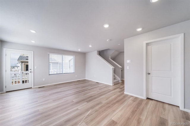 unfurnished living room with light wood-style flooring, stairs, baseboards, and recessed lighting