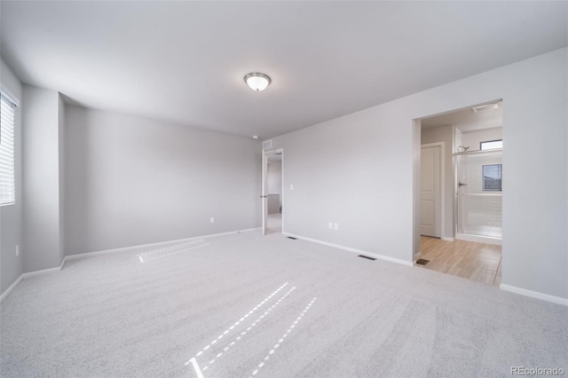 unfurnished bedroom featuring carpet flooring, baseboards, and ensuite bath