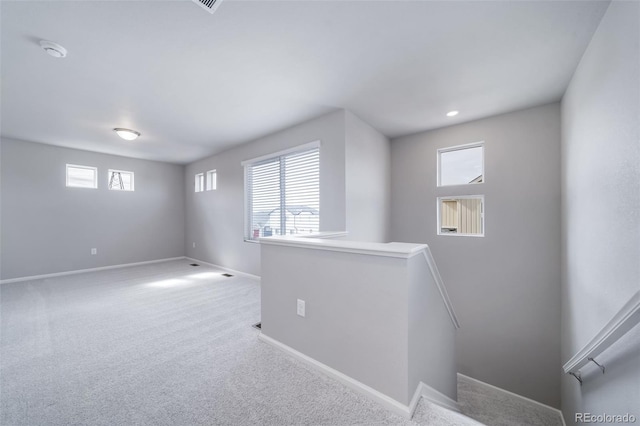 basement featuring baseboards, plenty of natural light, and carpet