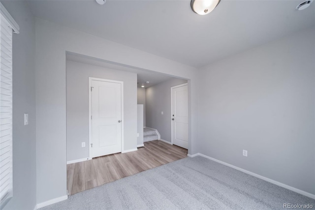 empty room with baseboards, carpet, and wood finished floors