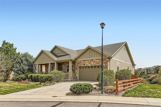 craftsman-style house with board and batten siding, a porch, fence, concrete driveway, and stone siding