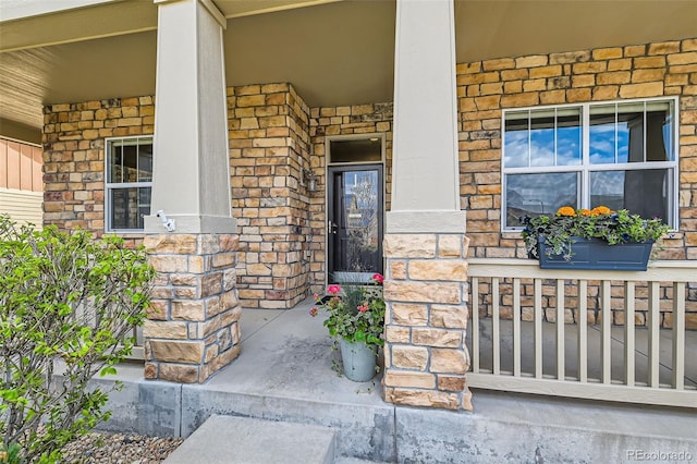 view of exterior entry featuring covered porch and stone siding