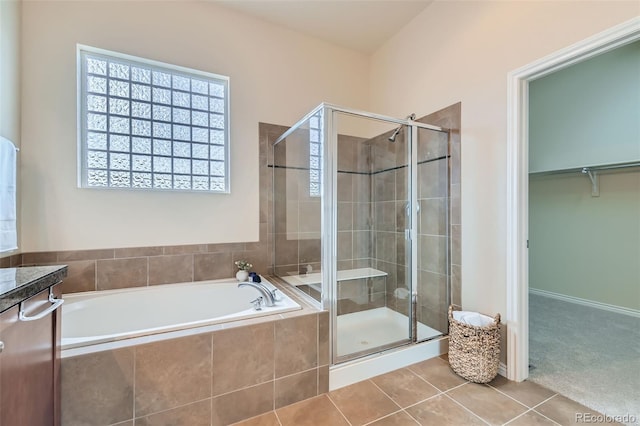 full bath with tile patterned floors, a stall shower, a bath, and a walk in closet