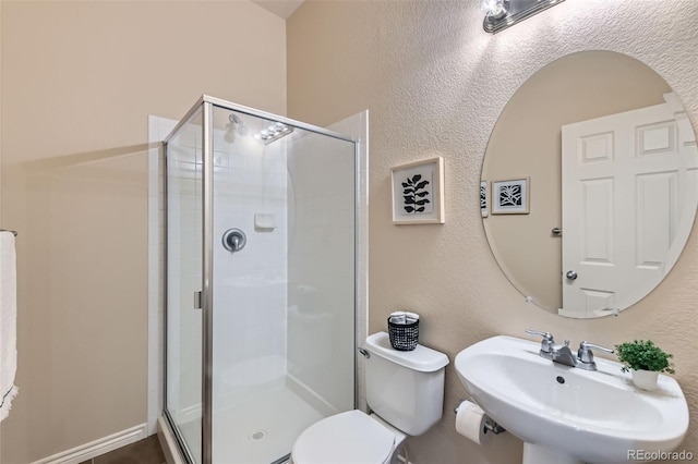 bathroom featuring a sink, a shower stall, and toilet