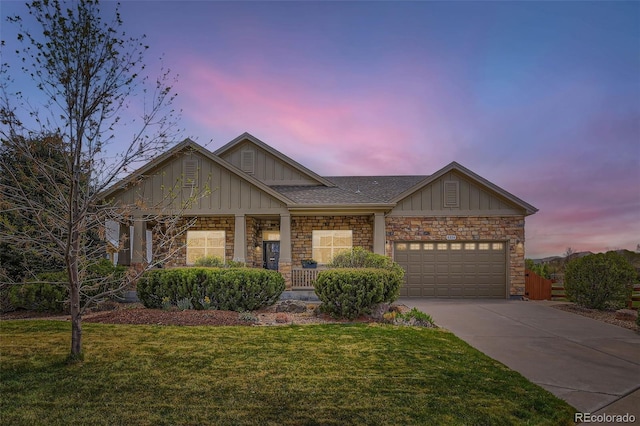 view of front facade with an attached garage, stone siding, board and batten siding, a front yard, and driveway