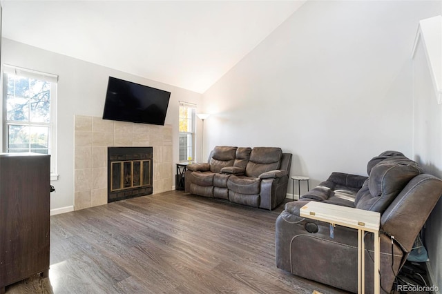 living room with a tiled fireplace, high vaulted ceiling, wood-type flooring, and a wealth of natural light