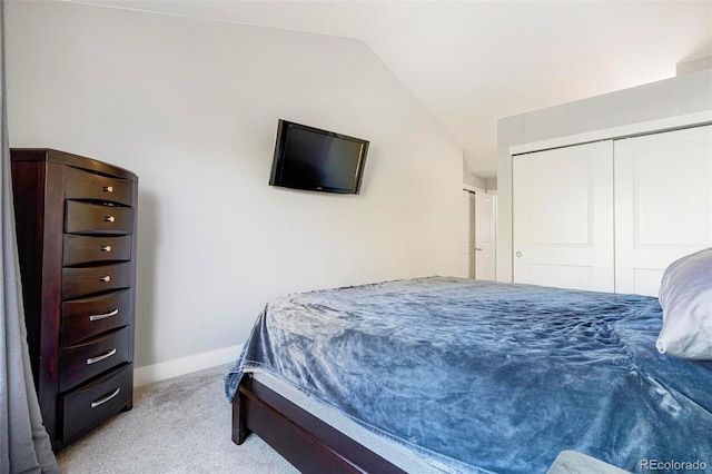 bedroom with a closet, light carpet, and lofted ceiling