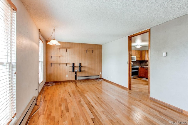 empty room with a baseboard radiator, wood finished floors, a textured ceiling, and wood walls