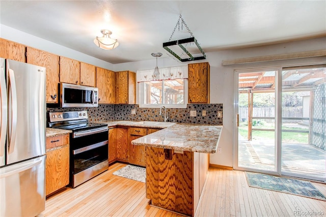 kitchen featuring stainless steel appliances, a sink, light wood-style flooring, and decorative backsplash
