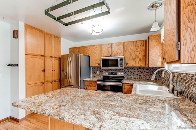 kitchen with appliances with stainless steel finishes, a sink, a peninsula, and decorative backsplash
