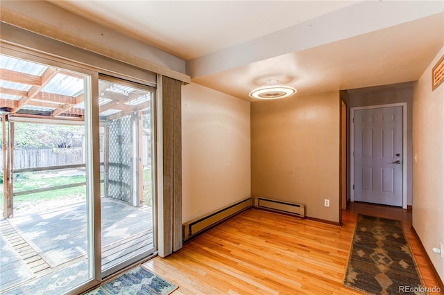 unfurnished room with light wood-style floors, baseboard heating, and baseboards