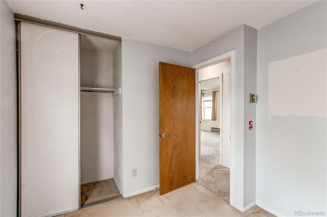 unfurnished bedroom featuring light colored carpet, a closet, and a textured ceiling