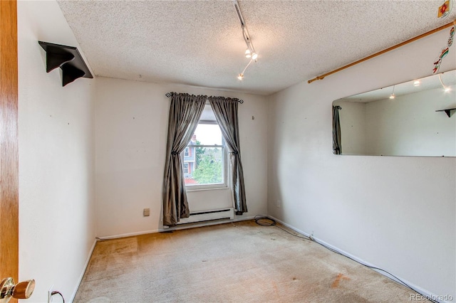 spare room featuring track lighting, baseboard heating, a textured ceiling, carpet floors, and baseboards