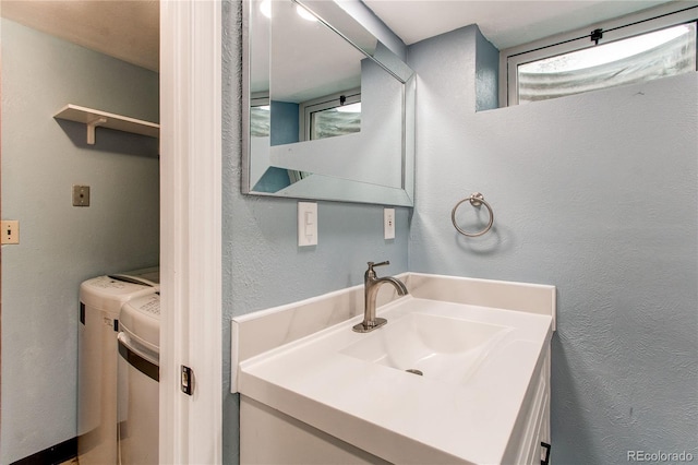 bathroom featuring washing machine and dryer, vanity, and a textured wall