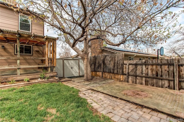 view of yard with a storage unit, fence, an outbuilding, and a patio