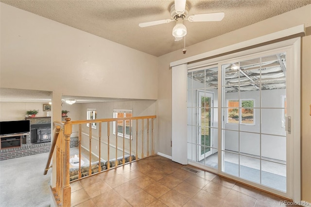 entryway with a wood stove, a textured ceiling, and ceiling fan