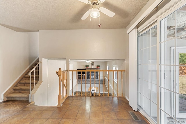 stairs with a textured ceiling, tile patterned floors, and ceiling fan