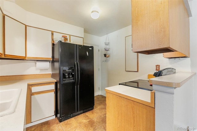 kitchen with white cabinets, sink, and black fridge with ice dispenser