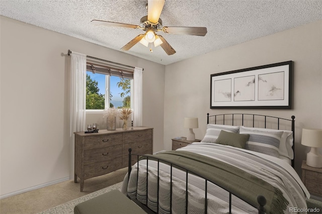 carpeted bedroom with ceiling fan and a textured ceiling